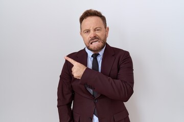Middle age business man with beard wearing suit and tie pointing aside worried and nervous with forefinger, concerned and surprised expression