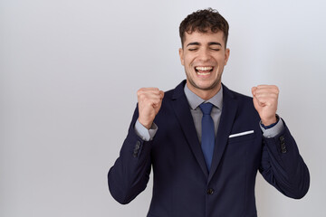 Young hispanic business man wearing suit and tie excited for success with arms raised and eyes closed celebrating victory smiling. winner concept.
