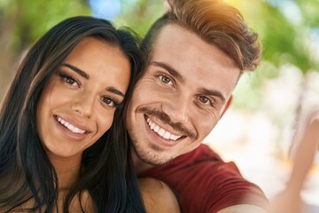 Naklejka premium Man and woman couple making selfie by smartphone at park