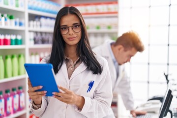 Obraz premium Man and woman pharmacists using touchpad and computer working at pharmacy