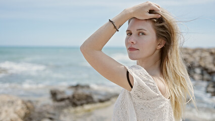 Fototapeta na wymiar Young blonde woman tourist touching hair at beach