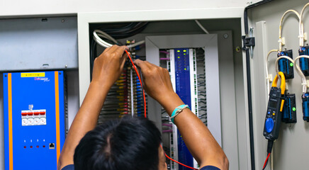 Electrician work tester measuring voltage and current of power electric line in electrical cabinet...