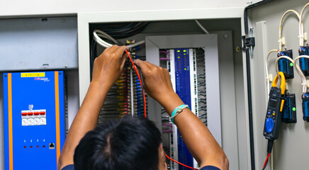 Electrician work tester measuring voltage and current of power electric line in electrical cabinet control, Professional man uses tool commissioning test or checking circuit for protection system.