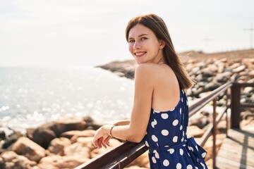 Young blonde woman tourist smiling confident leaning on balustrade at seaside