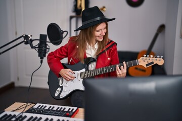 Obraz premium Young blonde woman musician singing song playing electrical guitar at music studio
