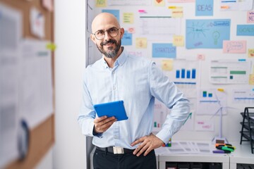 Young bald man business worker smiling confident using touchpad at office