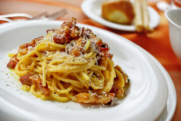 Plate with spaghetti carbonara on a laid table