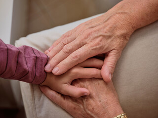 Unrecognizable grandparent touching hand of grandchild