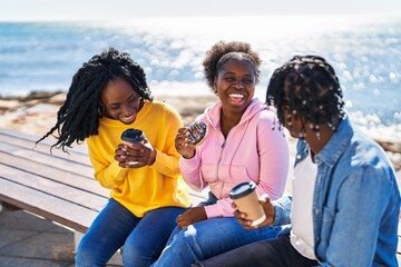 African american friends having breakfast sitting on bench at seaside