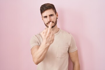 Hispanic man with beard standing over pink background showing middle finger, impolite and rude fuck...
