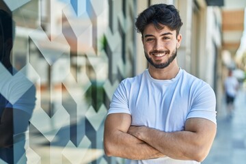 Young hispanic man smiling confident standing with arms crossed gesture at street