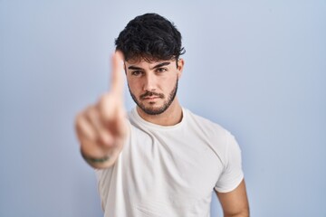 Fototapeta premium Hispanic man with beard standing over white background pointing with finger up and angry expression, showing no gesture