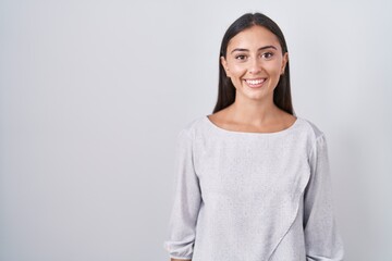 Young hispanic woman standing over white background with a happy and cool smile on face. lucky...