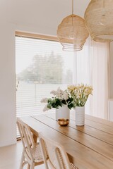 Interior shot of a contemporary styled living space with a wooden table and vases full of flowers