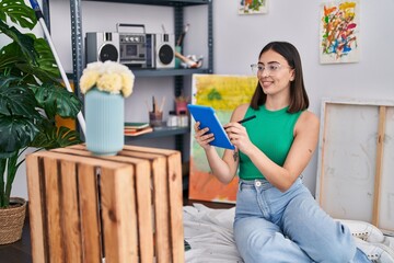 Young hispanic woman artist drawing on touchpad at art studio