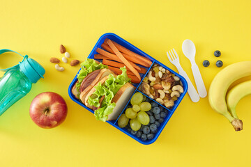 Healthy break-time option for school concept. Top-down view of lunchbox filled with sandwiches and...