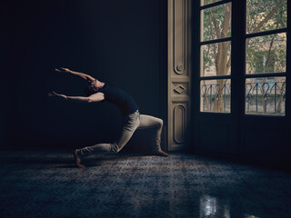 Flexible artist doing pose in dark apartment