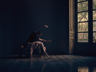 Ballet dancer dancing in dark ball room
