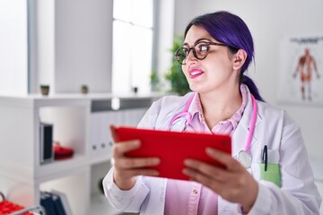 Young beautiful plus size woman doctor using touchpad standing at clinic