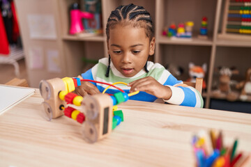 African american boy playing with blocks game sitting on table at kindergarten