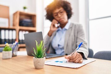 African american woman business worker talking on smartphone writing on document at office