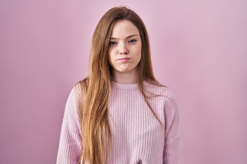 Young caucasian woman standing over pink background puffing cheeks with funny face. mouth inflated with air, crazy expression.