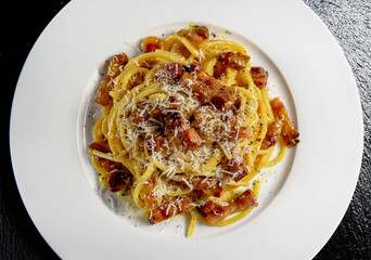 Top view of plate with spaghetti carbonara and grated cheese