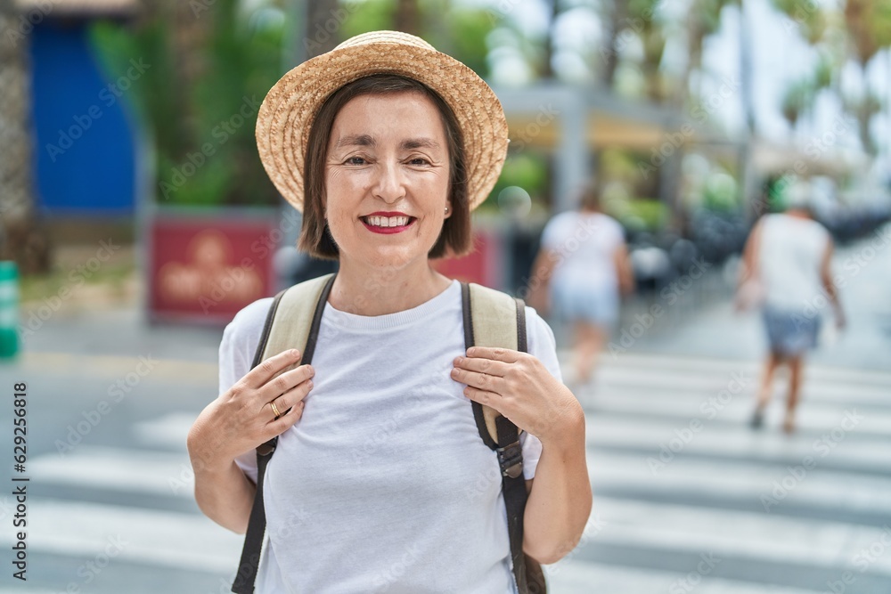 Wall mural middle age woman tourist smiling confident wearing backpack at street