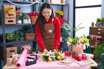 Young chinese woman florist make bouquet of flowers at flower shop