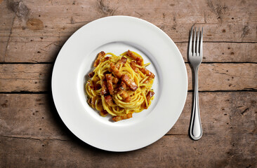 Top view of plate with spaghetti carbonara on wooden table