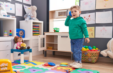 Adorable caucasian boy playing with balls standing at kindergarten