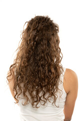 Rear view of a woman with long brown wavy hair on a white background
