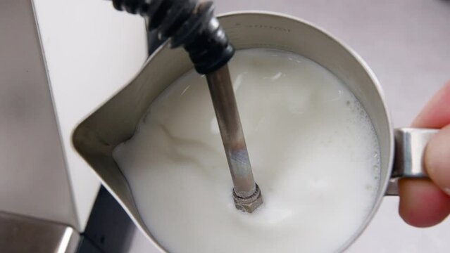 Close-up slow-motion view of steaming milk for cappuccino making