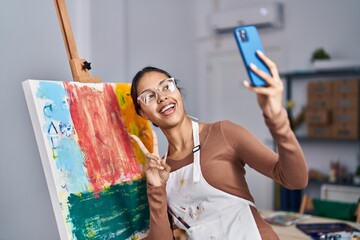 Young african american woman artist smiling confident making selfie by the smartphone at art studio