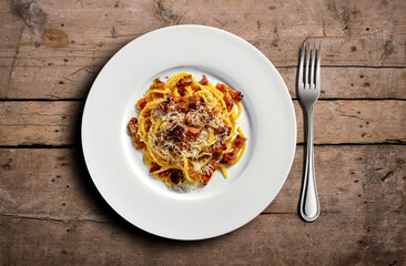 Top view of plate with spaghetti carbonara on wooden table