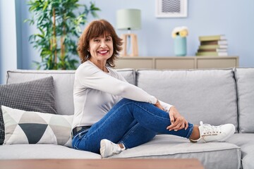 Middle age woman smiling confident sitting on sofa at home