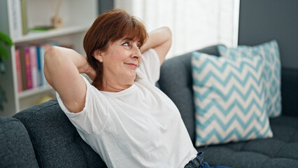 Middle age woman relaxed with hands on head sitting on sofa home