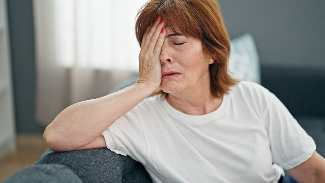 Middle age woman stressed sitting on sofa home