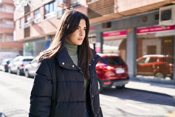 Young beautiful hispanic woman looking to the side with serious expression at street