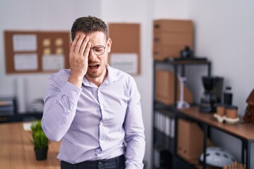 Young hispanic man at the office yawning tired covering half face, eye and mouth with hand. face...