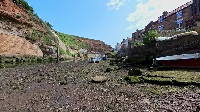 Staithes, North Yorkshire, UK &ndash; June 22 2023. Fishing boat beached on the bed of Staithes Beck, a small river in the coastal town of Staithes in North Yorkshire, at low tide