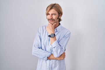 Caucasian man with mustache standing over white background looking confident at the camera smiling...