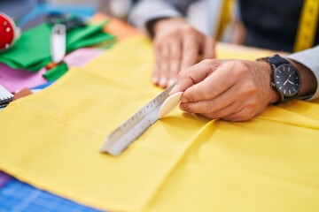 Young blond man tailor make mark on cloth at clothing factory