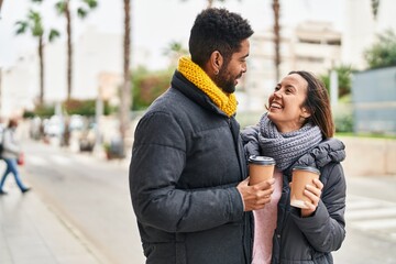 Man and woman couple smiling confident drinking coffee at street