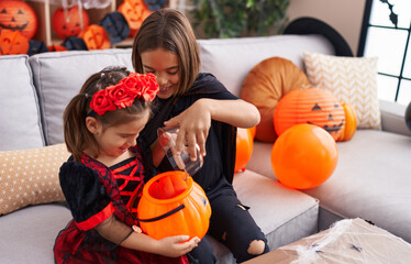 Adorable boy and girl having halloween party putting candies in pumpkin basket at home