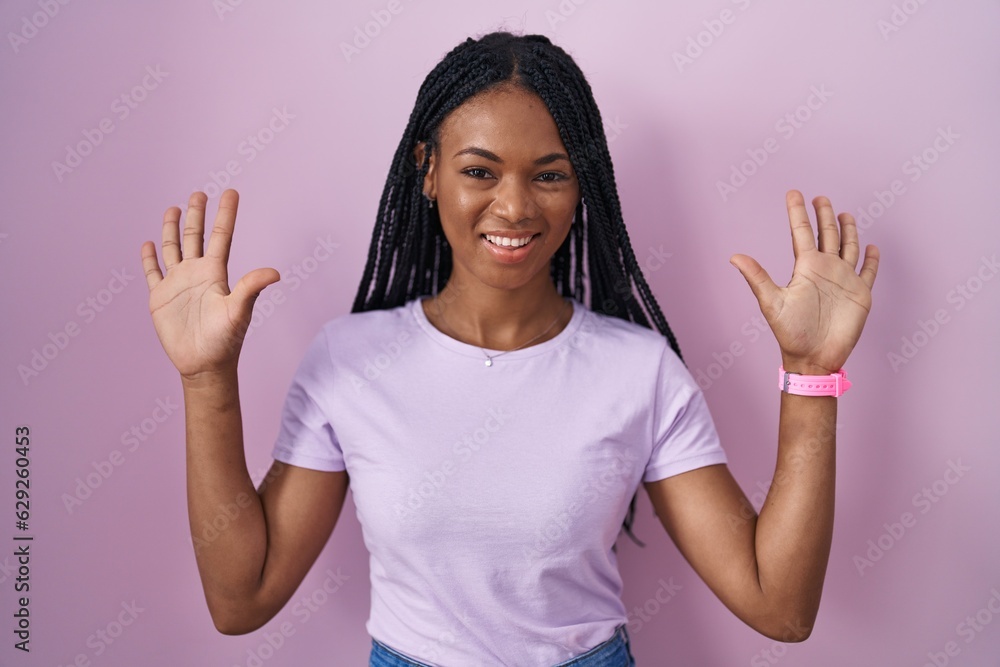 Poster african american woman with braids standing over pink background showing and pointing up with finger