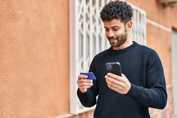 Young arab man using smartphone and credit card at street