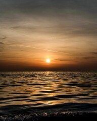 Obraz premium the sun is setting over the ocean at dusk on the beach