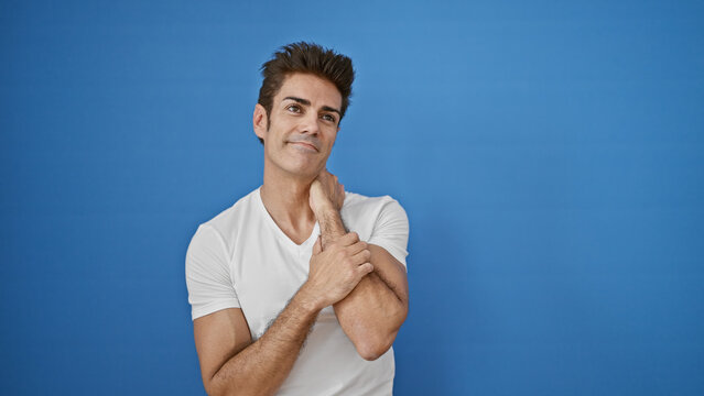 Young hispanic man smiling confident looking up over isolated blue background