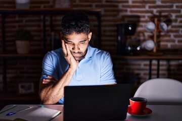 Fototapeta na wymiar Hispanic man with beard using laptop at night thinking looking tired and bored with depression problems with crossed arms.